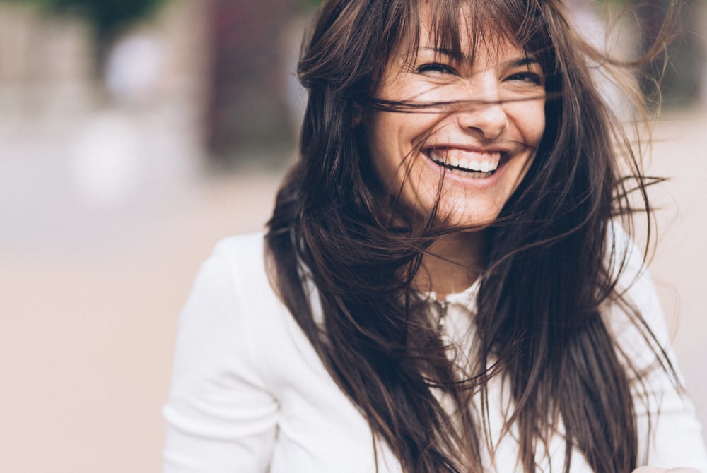 Hair blowing in the face of smiling woman who has had dermal fillers